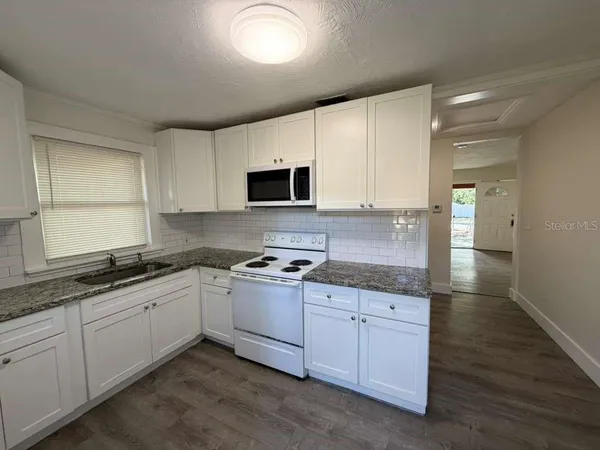 a kitchen with granite countertop a sink a stove and cabinets