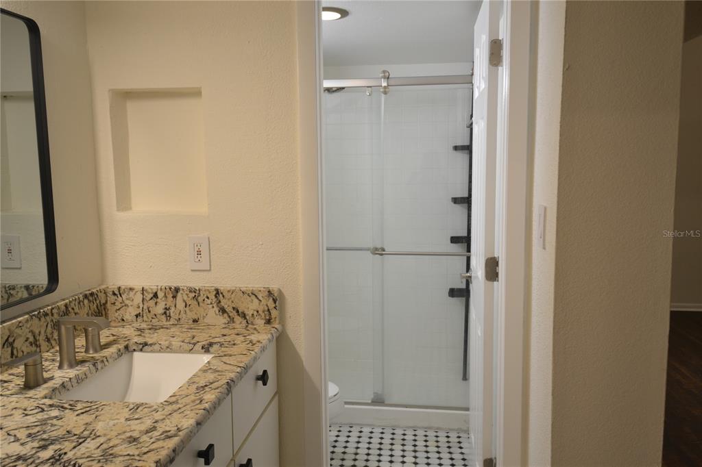 2585 Countryside Boulevard, Unit 4307 Clearwater, FL 33761 - Photo 22 of 32 a bathroom with a granite countertop sink a mirror and shower