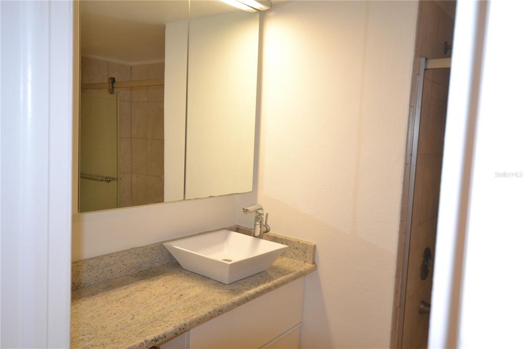 2585 Countryside Boulevard, Unit 4307 Clearwater, FL 33761 - Photo 7 of 32 a bathroom with a granite countertop sink and a mirror