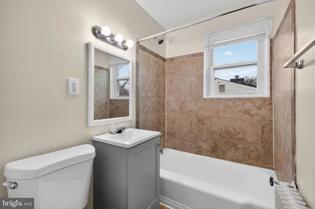 a bathroom with a granite countertop sink a toilet a shower and a mirror