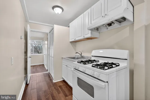 a kitchen with granite countertop a sink stove and cabinets