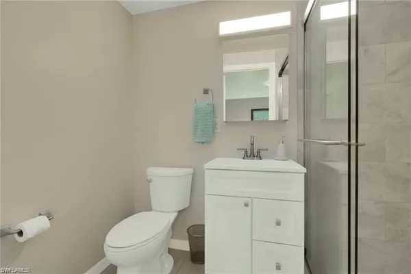 a bathroom with a granite countertop toilet a sink and a mirror