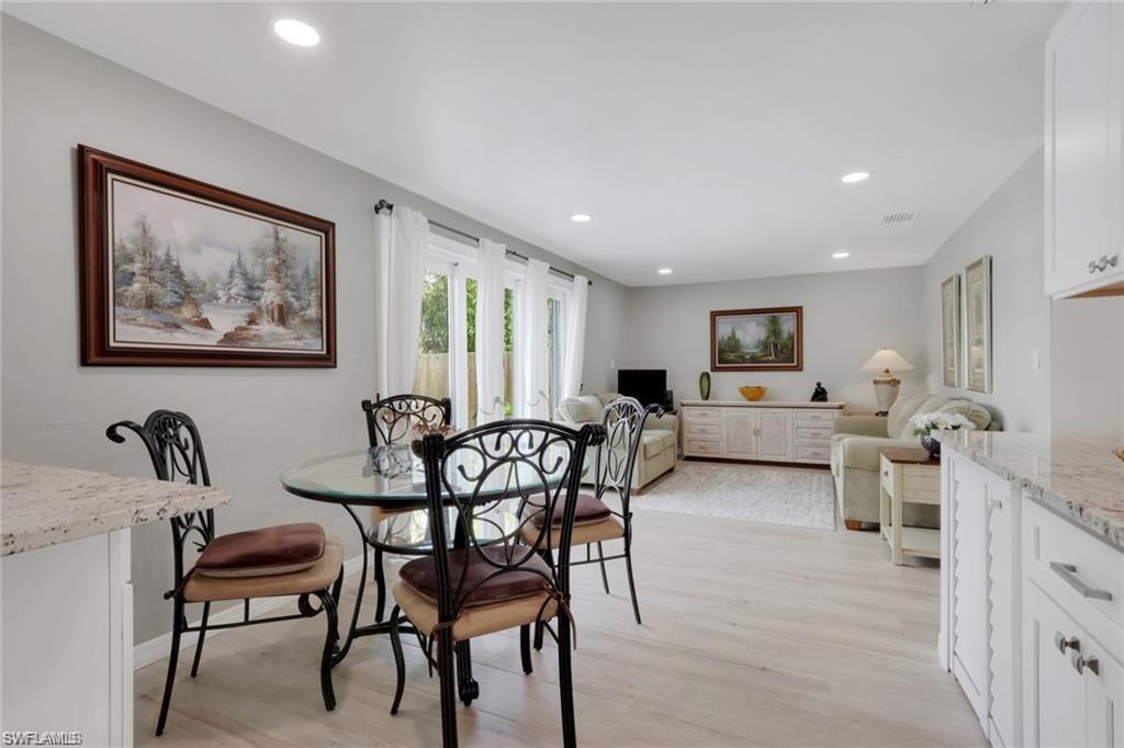 829 107th Avenue North Naples, FL 34108 - Photo 3 of 34 a living room with furniture and a dining table with wooden floor