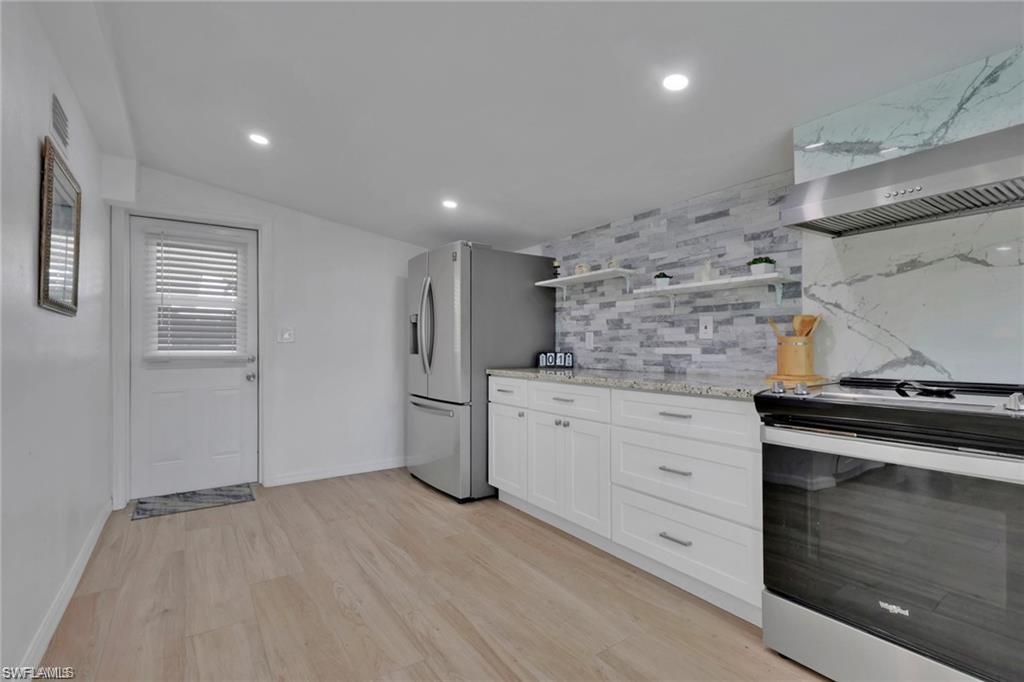 829 107th Avenue North Naples, FL 34108 - Photo 8 of 34 a kitchen with granite countertop white cabinets and white appliances