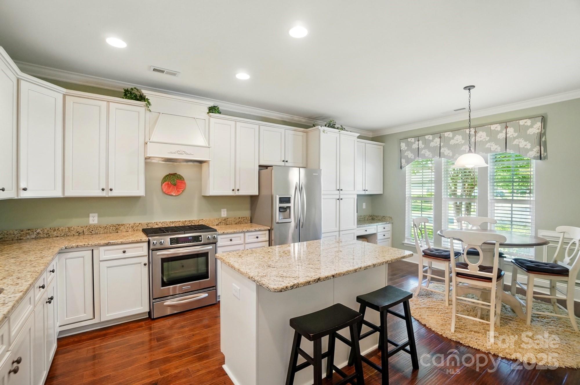 1974 Links View Drive Fort Mill, SC 29707 - Photo 4 of 30 a kitchen with stainless steel appliances granite countertop a stove top oven a refrigerator a sink and white cabinets with wooden floor