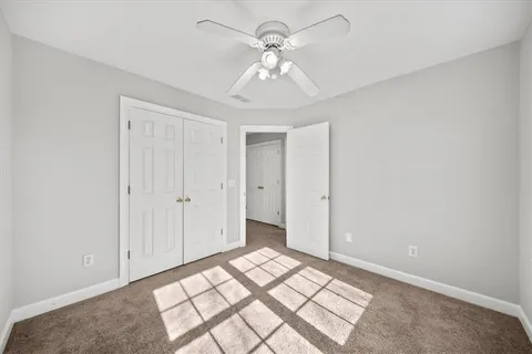 a view of a livingroom with a ceiling fan & cabinets