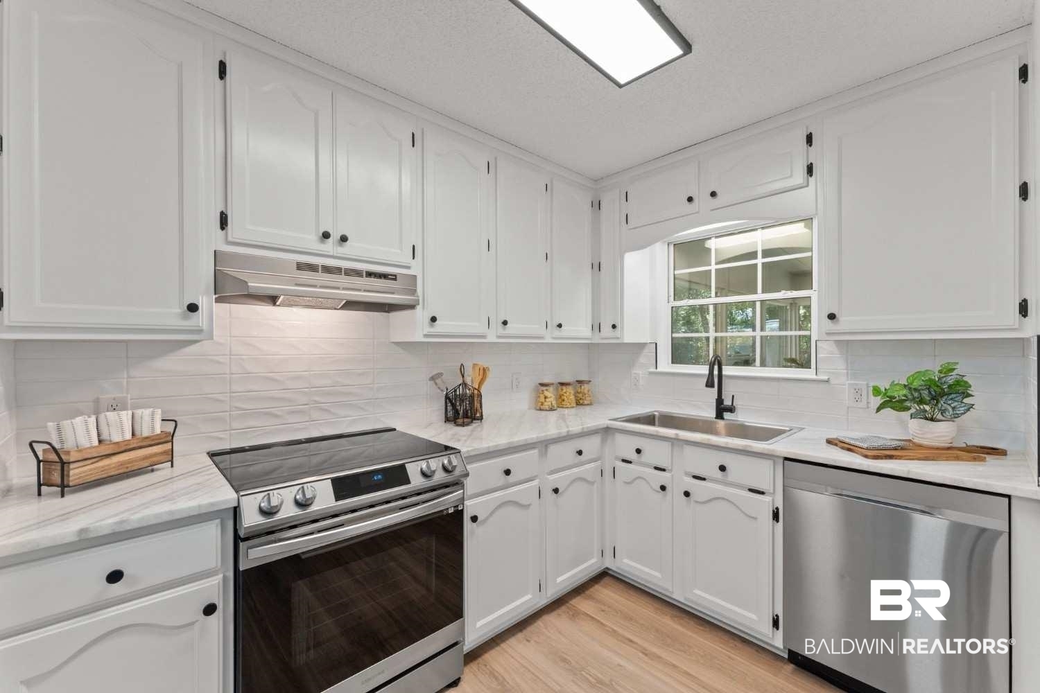 10251 Windmill Road Fairhope, AL 36532 - Photo 24 of 44 Kitchen featuring appliances with stainless steel finishes, under cabinet range hood, white cabinetry, and tasteful backsplash