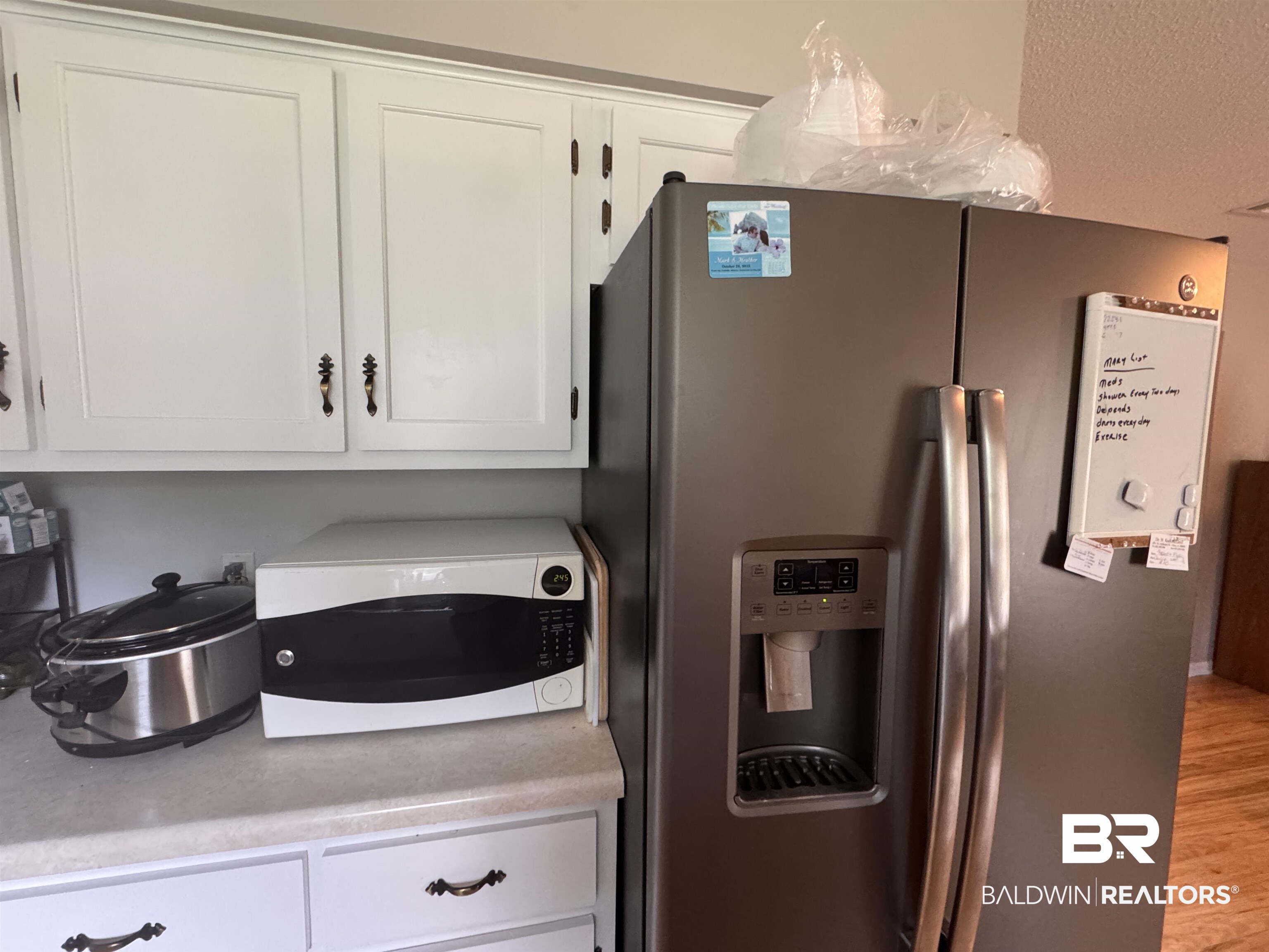 15148 Highland Circle Foley, AL 36535 - Photo 18 of 47 Kitchen with stainless steel fridge with ice dispenser, white microwave, white cabinets, and light countertops