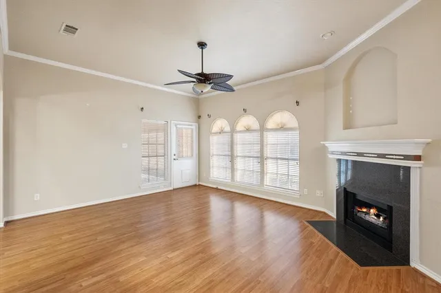 a view of an empty room with wooden floor fireplace and a window