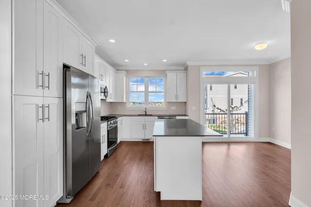 a kitchen with kitchen island wooden floors appliances and cabinets