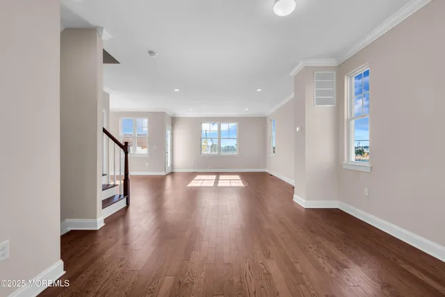 a view of a big room with wooden floor and windows