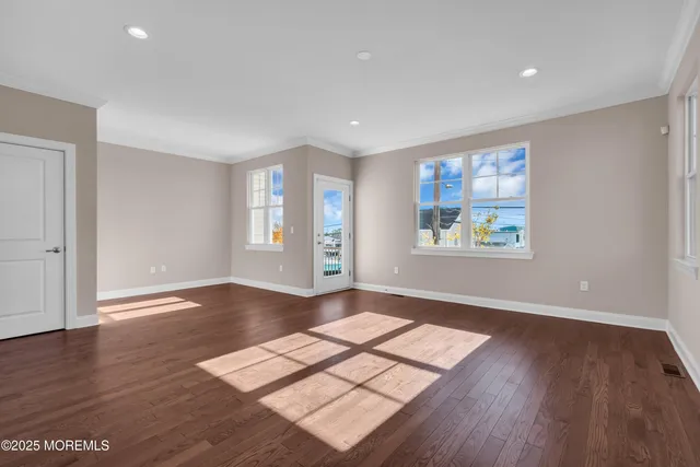 a view of an empty room with window and wooden floor