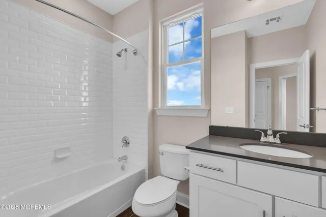 a bathroom with a granite countertop sink a toilet and shower