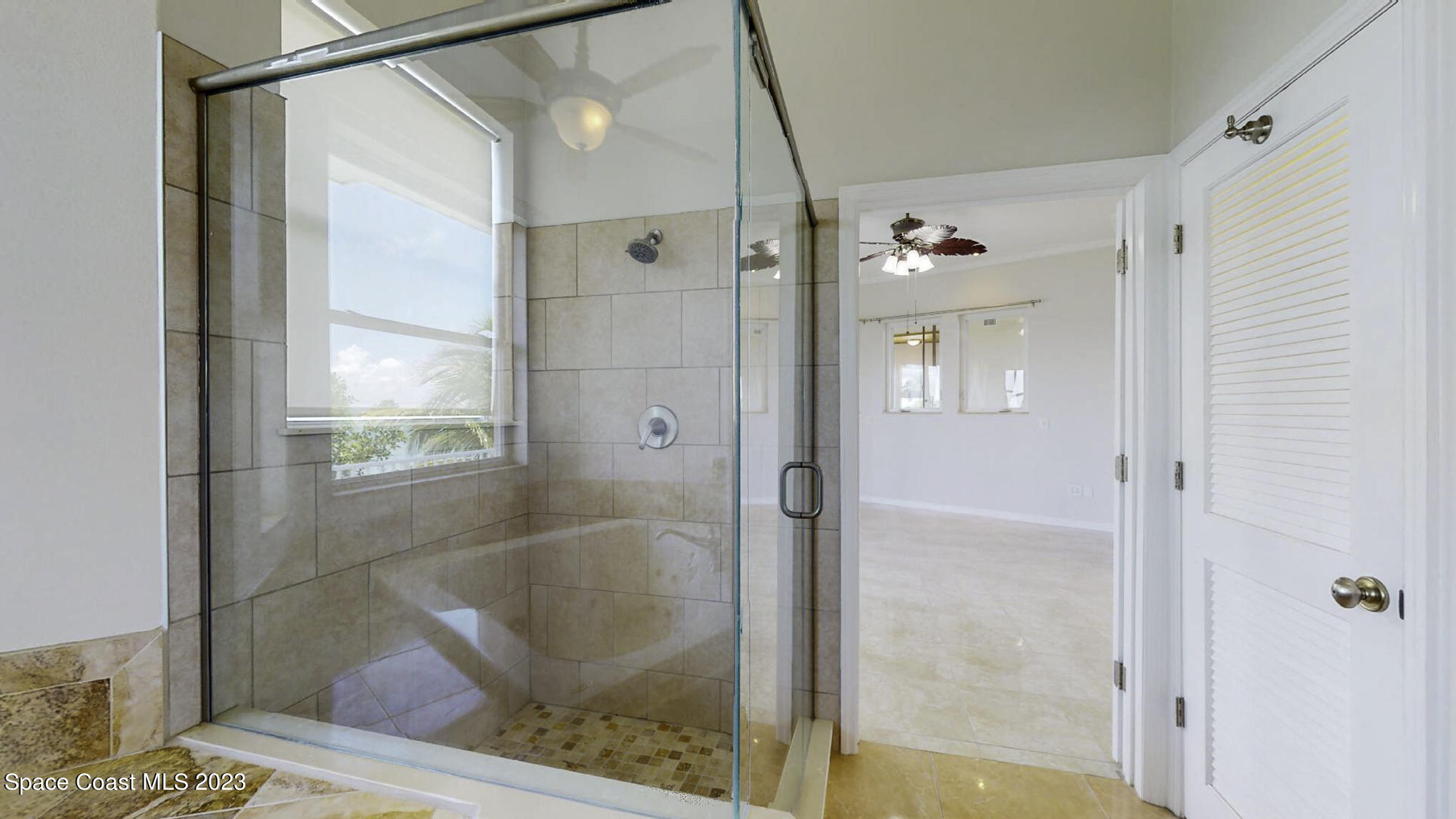21 West Point Drive, Unit 101 Cocoa Beach, FL 32931 - Photo 33 of 59 a bathroom with a glass shower door and a window