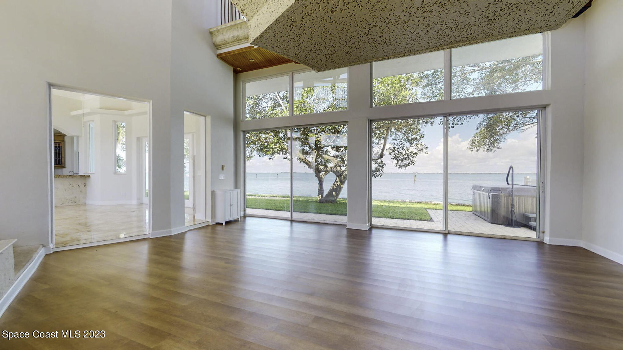 21 West Point Drive, Unit 101 Cocoa Beach, FL 32931 - Photo 9 of 59 a view of an empty room with wooden floor and a window