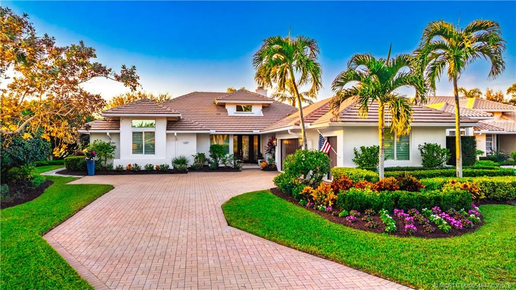 1257 Southeast Brewster Place Stuart, FL 34997 - Photo 1 of 35 a front view of a house with a garden and plants