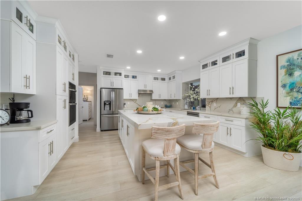 1257 Southeast Brewster Place Stuart, FL 34997 - Photo 17 of 35 a kitchen with white cabinets and stainless steel appliances