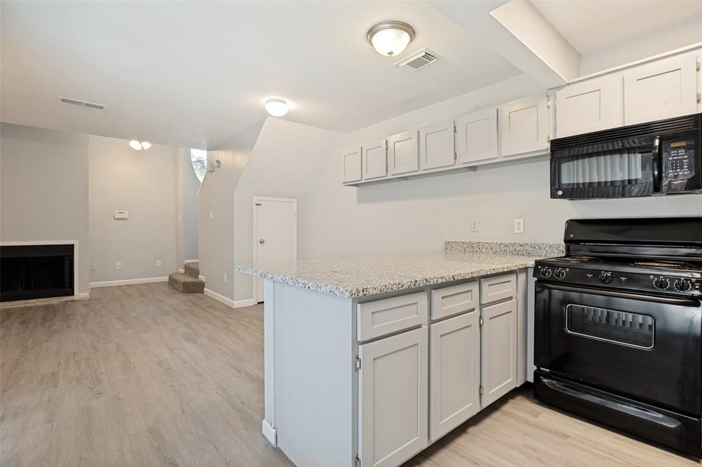 622 West Union Bower Road Irving, TX 75061 - Photo 2 of 13 Kitchen area featuring an island with a speckled countertop, light gray cabinetry, and a black range with an overhead microwave