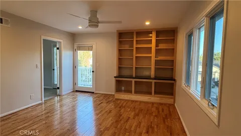 a view of an empty room with a window and wooden floor