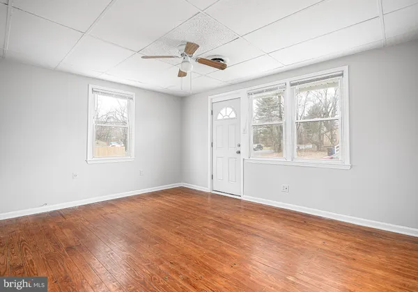 a view of an empty room with a window and wooden floor