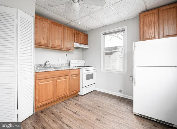 a kitchen with stainless steel appliances granite countertop a refrigerator a microwave oven a sink dishwasher and white cabinets with wooden floor