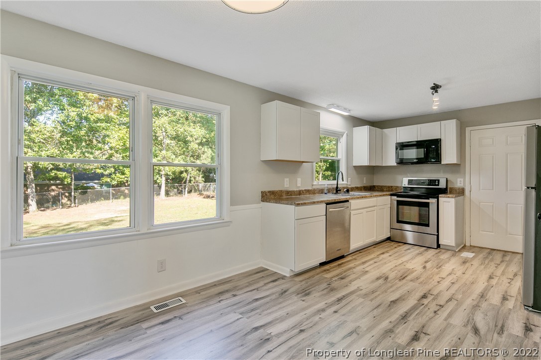 711 Bronco Road Fayetteville, NC 28303 - Photo 11 of 42 a kitchen with granite countertop a stove top oven a sink dishwasher and a refrigerator with wooden floor