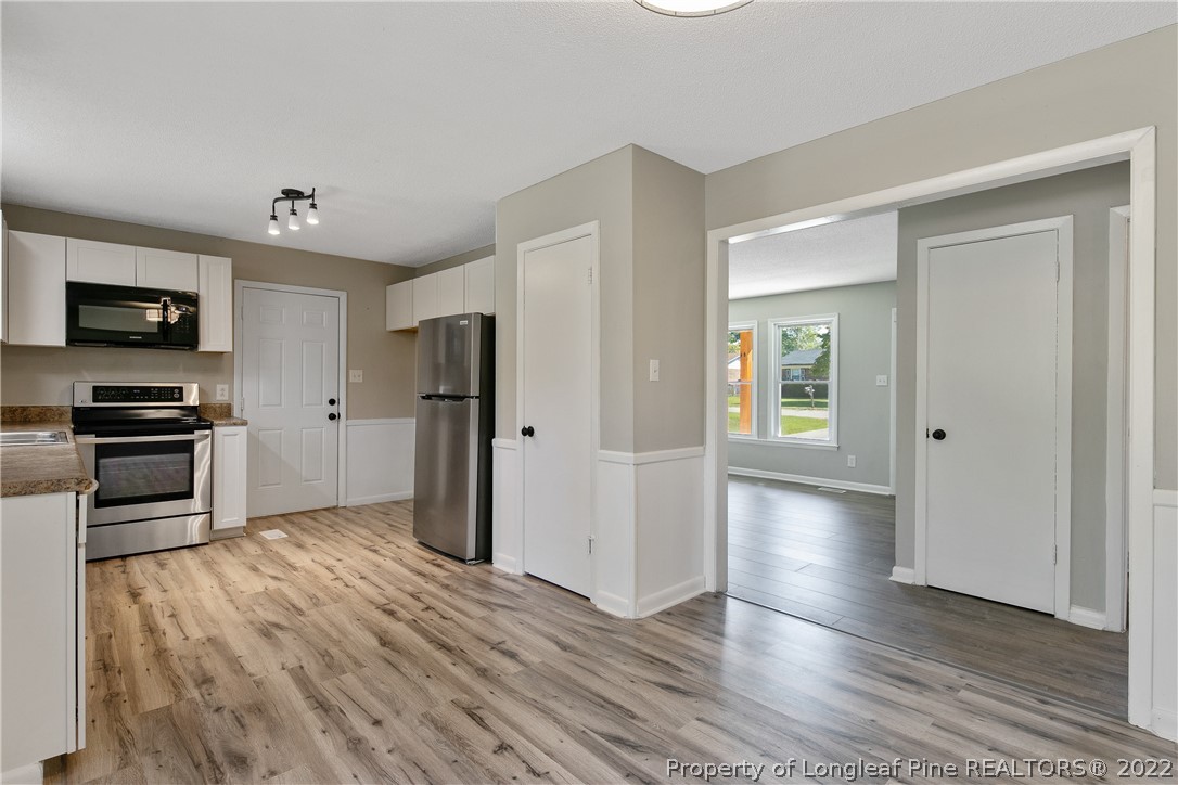 711 Bronco Road Fayetteville, NC 28303 - Photo 13 of 42 a an empty room with wooden floor and a kitchen