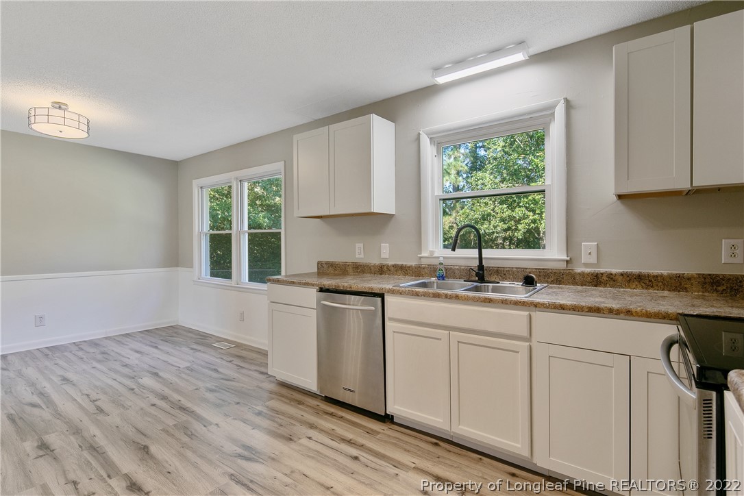 711 Bronco Road Fayetteville, NC 28303 - Photo 21 of 42 a kitchen with granite countertop white cabinets a sink and dishwasher with wooden floor