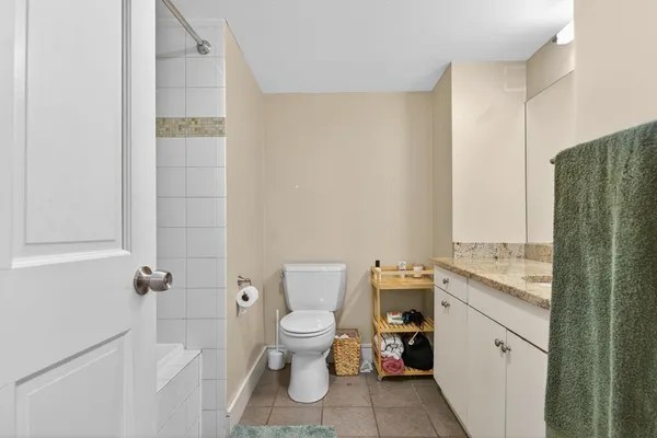 a bathroom with a granite countertop toilet a sink and a mirror