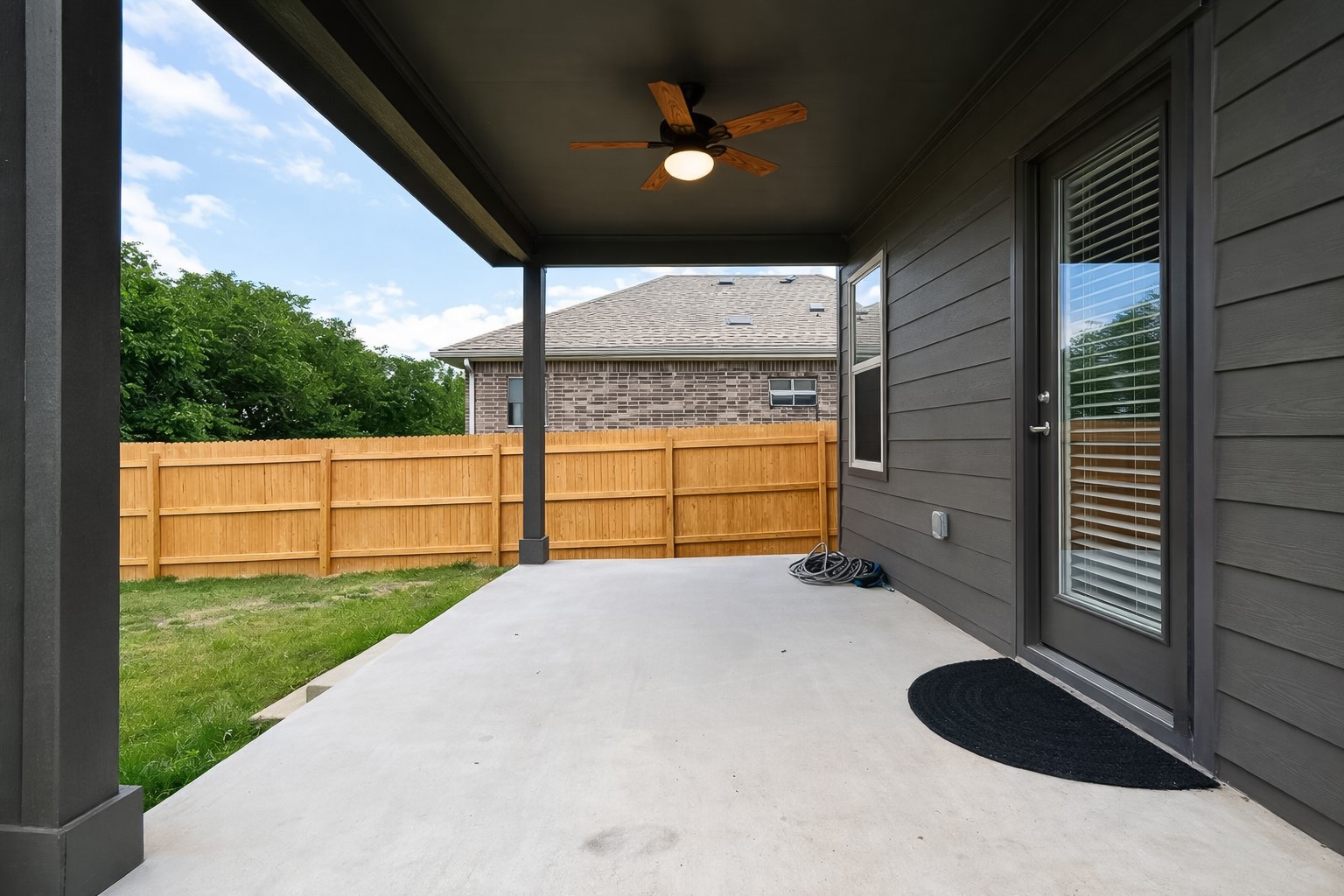 940 Paddock Lane Georgetown, TX 78626 - Photo 7 of 32 Covered patio with a ceiling fan, a full-lite exterior door with integrated blinds, and a wood privacy fence bordering a grassy area