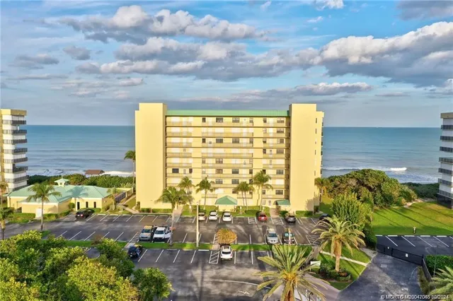 a open kitchen with stainless steel appliances granite countertop a refrigerator a sink dishwasher and a dining table with wooden floor