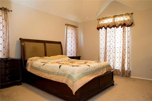 a bed sitting in a bedroom next to a window and a chandelier