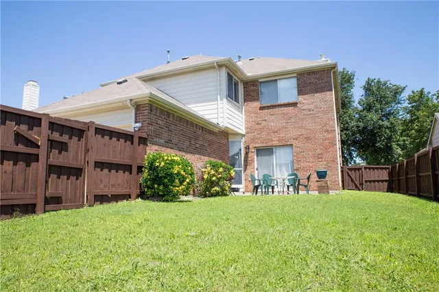 a view of a brick house with a big yard and large trees