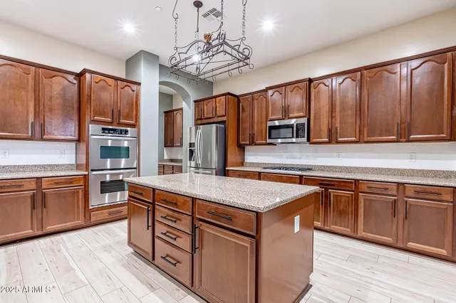 a kitchen with stainless steel appliances granite countertop wooden cabinets a stove top oven a sink and dishwasher