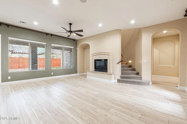 an empty room with wooden floor fireplace and windows
