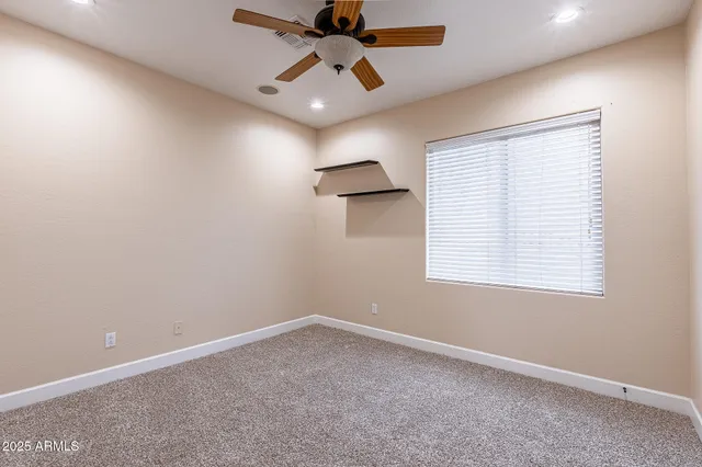 an empty room with a window and a fan