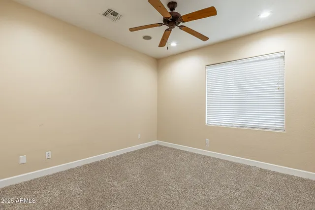 an empty room with a window and a fan