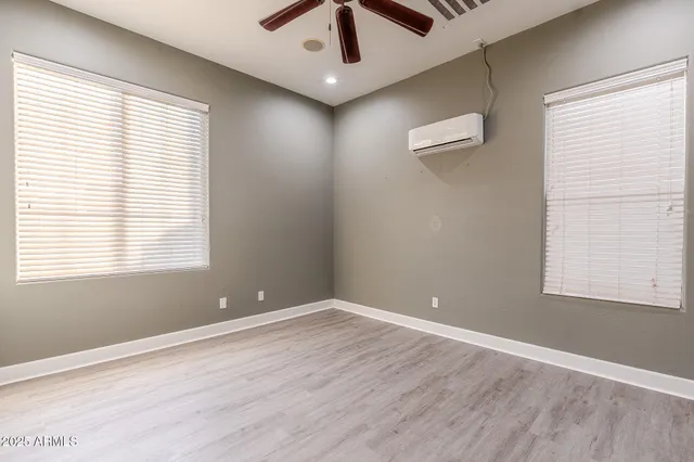 a view of empty room with wooden floor and fan