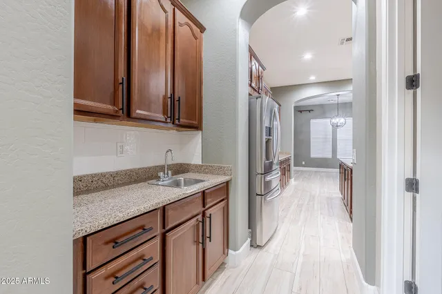 a hallway view with stainless steel appliances granite countertop a sink and dishwasher with wooden floor