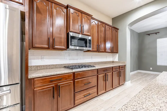 a kitchen with granite countertop wooden cabinets stainless steel appliances and a counter top space