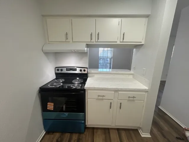 a kitchen with a stove and white cabinets
