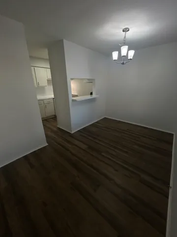 an empty room with wooden floor cabinets and entryway