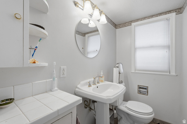 7576 South Jefferson Street Midvale, UT 84047 - Photo 16 of 53 Bathroom featuring a pedestal sink, white ceramic tile countertop, wall-mounted cabinet, and a window with blinds