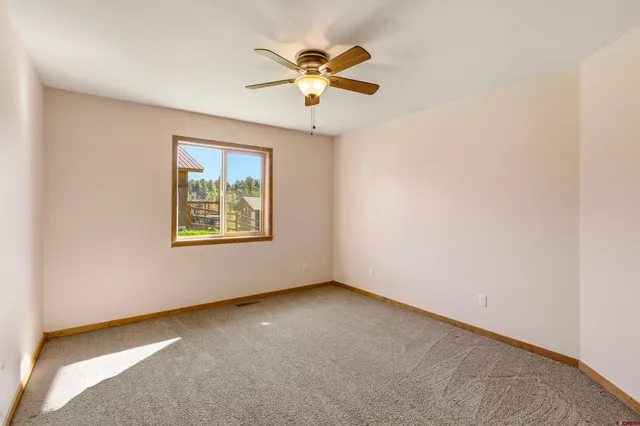 an empty room with window and ceiling fan