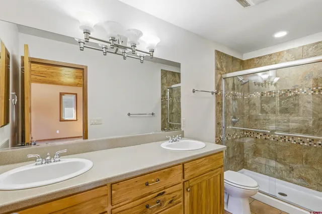 a bathroom with a granite countertop sink a toilet a mirror and shower
