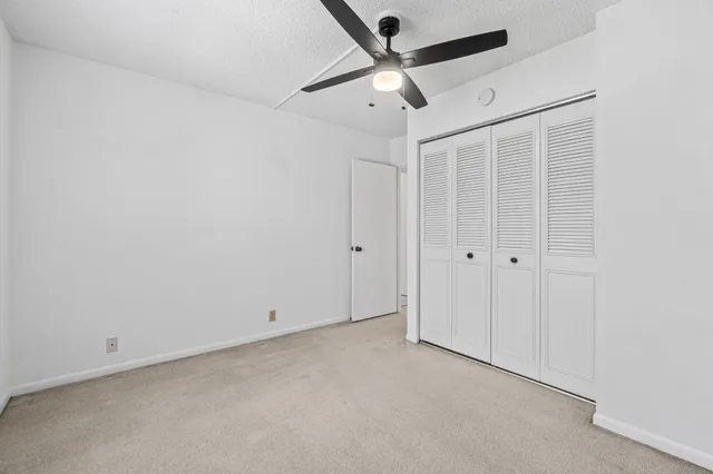 an empty room with a ceiling fan and window