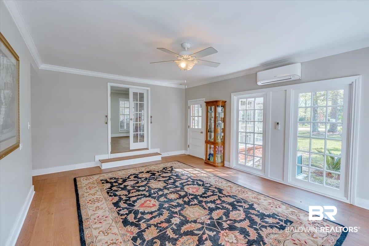 14160 Moffett Road Wilmer, AL 36587 - Photo 16 of 75 Doorway featuring ornamental molding, wood finished floors, a wall unit AC, and a ceiling fan