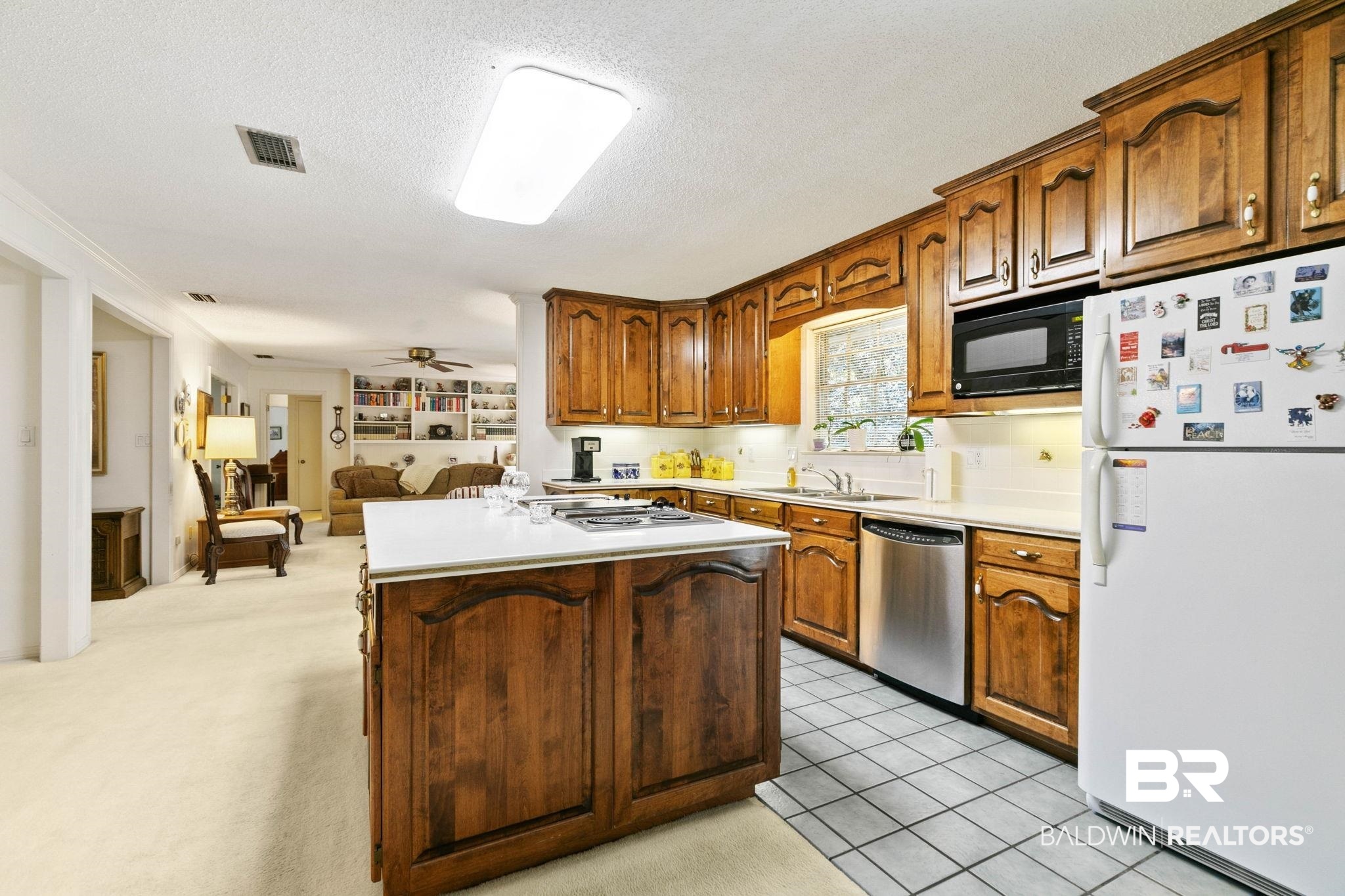 752 Evergreen Street Fairhope, AL 36532 - Photo 12 of 100 Kitchen featuring appliances with stainless steel finishes, light countertops, a textured ceiling, light tile patterned floors, and brown cabinetry