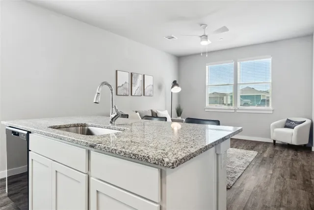 a kitchen with granite countertop a sink and dishwasher with wooden floor