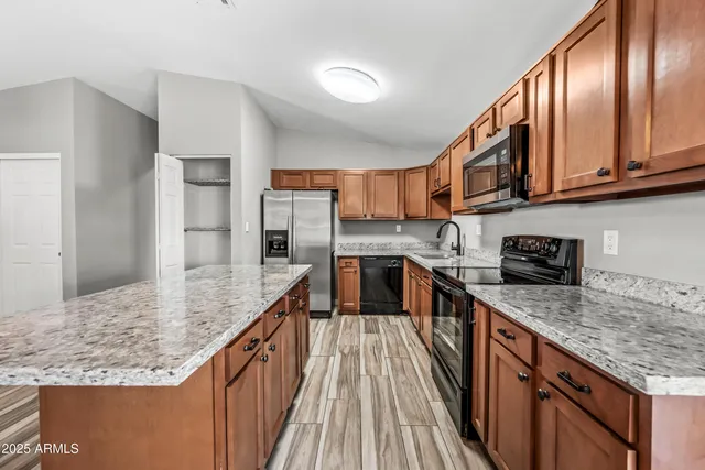 a kitchen with stainless steel appliances granite countertop a sink dishwasher stove and refrigerator